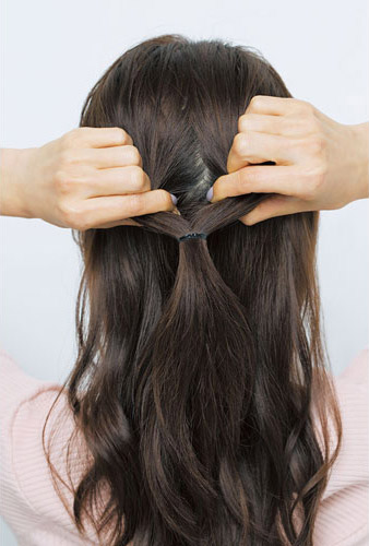 ハーフアップの結び目の上の髪を両手で広げている写真