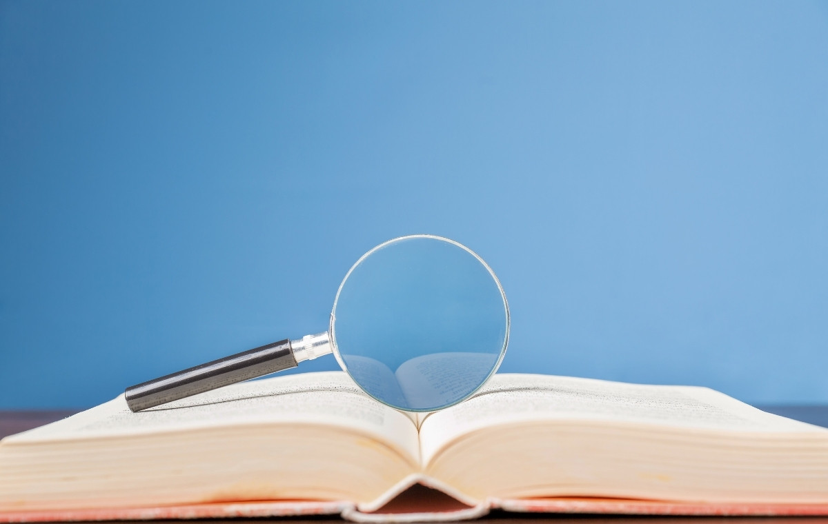 開いた辞書の上にルーペがおかれている写真