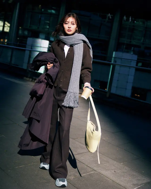 ブラウンのニットカーディガン×ブラウンパンツ×グレーマフラー×グレースニーカーコーデ