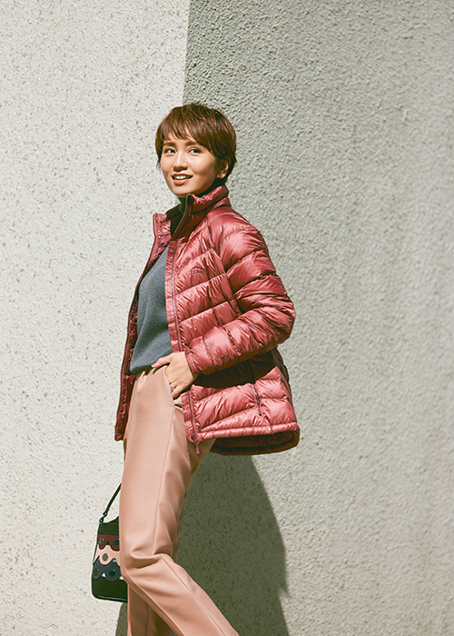 グレーのニットとくすんだピンクのパンツにローズピンクのミドル丈のダウンをはおったモデル写真