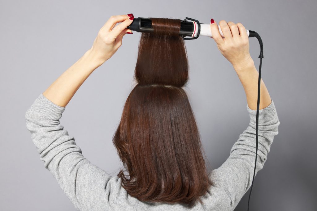 ハチ上の髪をコテで巻いているモデルの写真