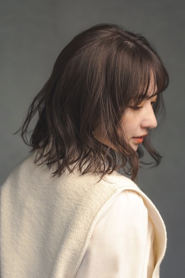 前髪ありの毛先にウェーブがかかったボブヘアの写真　横顔