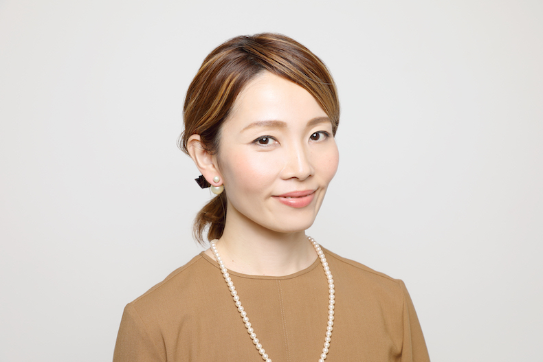 ふっくらとしたひとつ結びにえんじ色のリボンの形のヘアアクセをあしらった写真