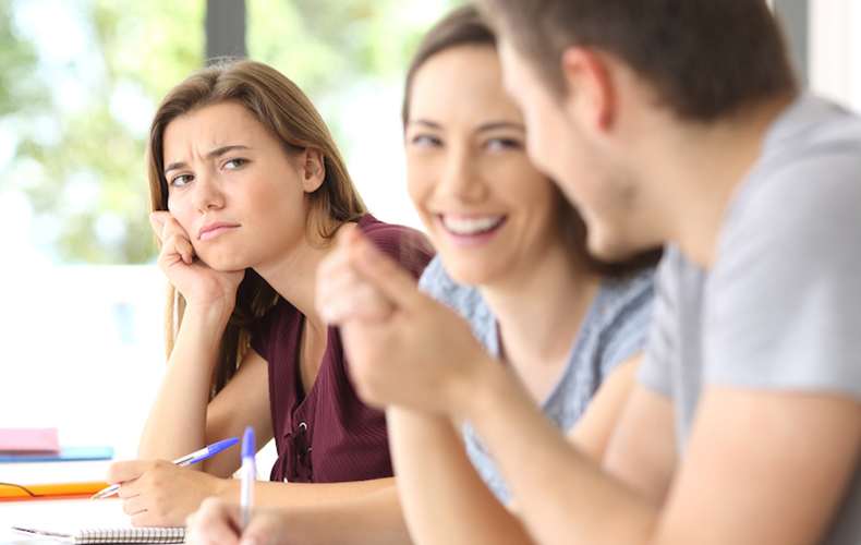 笑顔で会話する2人と、その2人を顰めっ面で頬杖をつきながら見ている人の写真