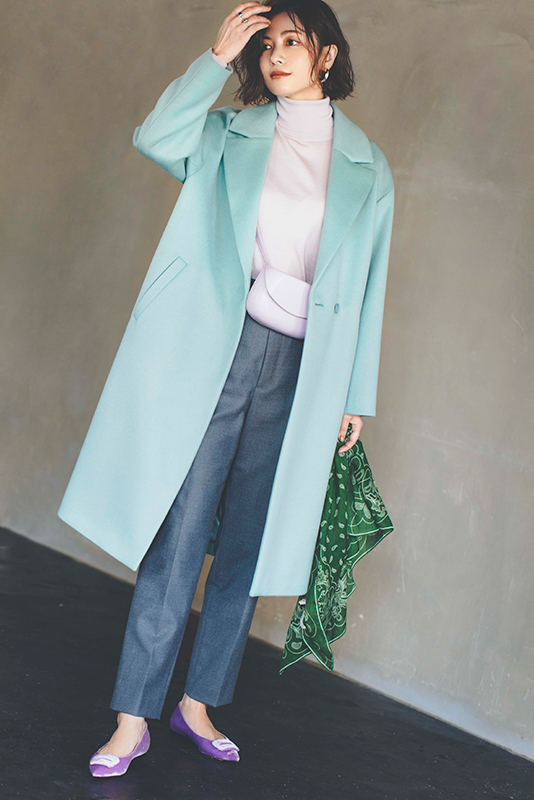 ラベンダー色のニットと暗いグレーのパンツに明るい水色のロングコートをはおったモデル写真