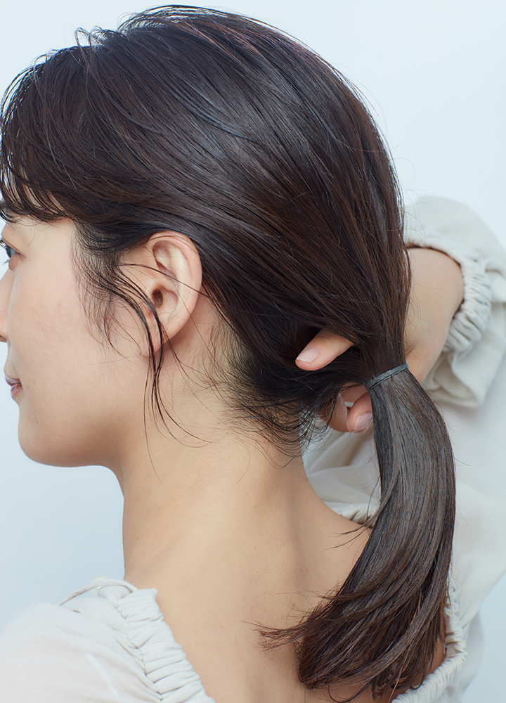 ひとつ結びの結び目の内側に人差し指を入れている後頭部写真