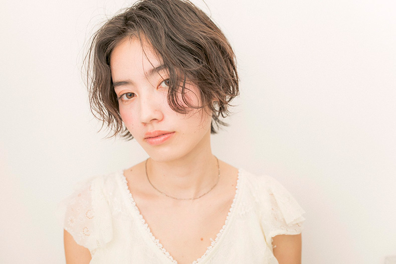 前髪なしでウェーブがかかったショートヘアのモデル写真　正面