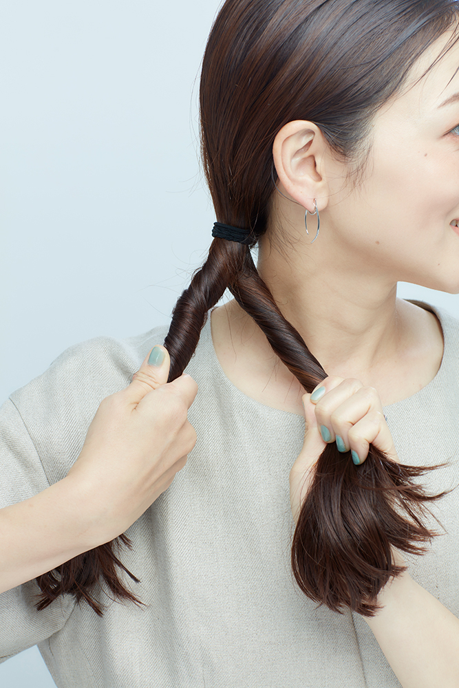 結んだ毛束をふたつに分け、それぞれをねじっている写真