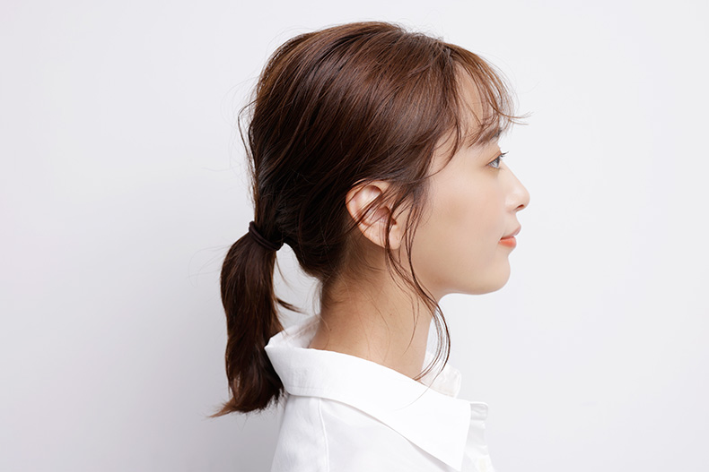下の方の位置でひとつ結びにした横顔写真
