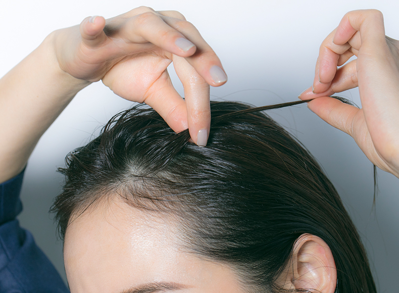 前髪の毛束を指でつまんでねじっている写真