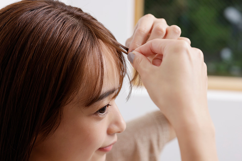 前髪を両手でつまむ女性のアップ
