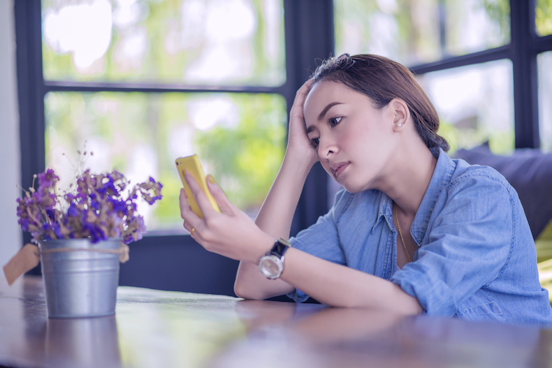 スマホを見ながら困っている女性の写真