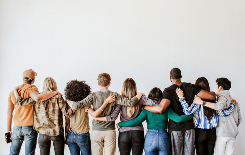 様々な人種・性別の人々が肩を組んでいる後ろ姿の写真