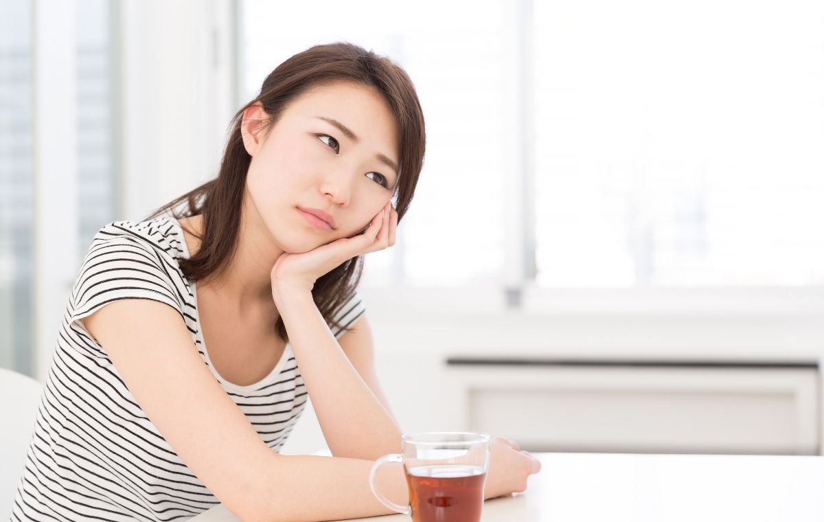 うんざりした表情で悩む女性の写真