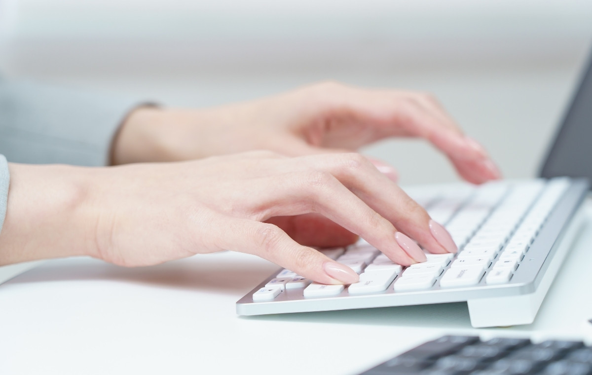 キーボードをタイプする女性の手元の写真