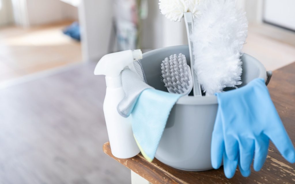 ゴム手袋やスプレー、ブラシなどの掃除用品がバケツに入っている写真