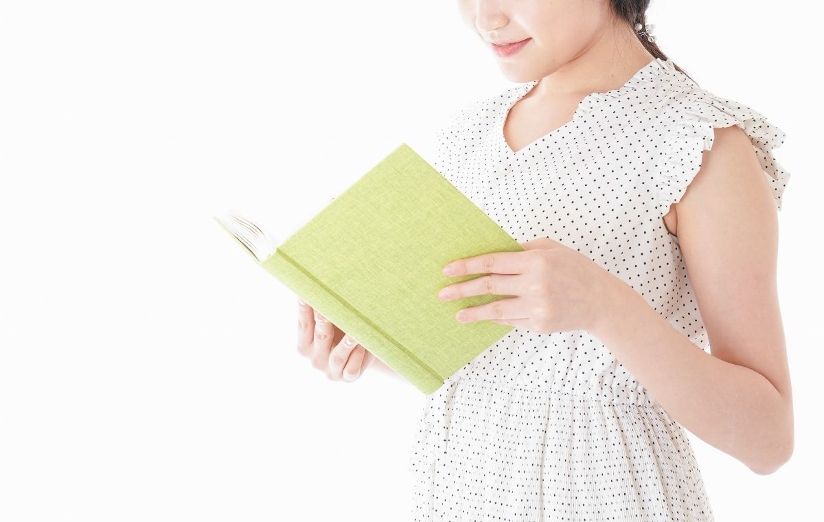 ワンピース姿の女性が本を読んでいる写真