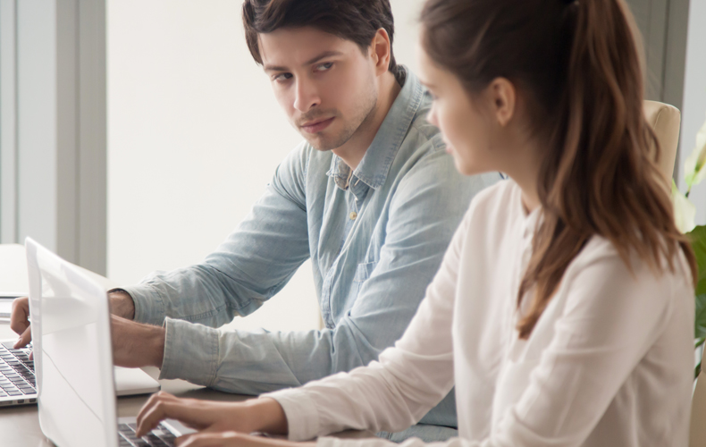 ノートパソコンの前でにらみ合う男女の写真