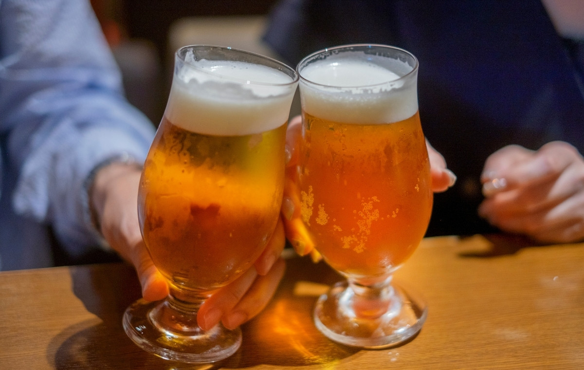 グラスに入ったビールで乾杯している男女の手元の写真