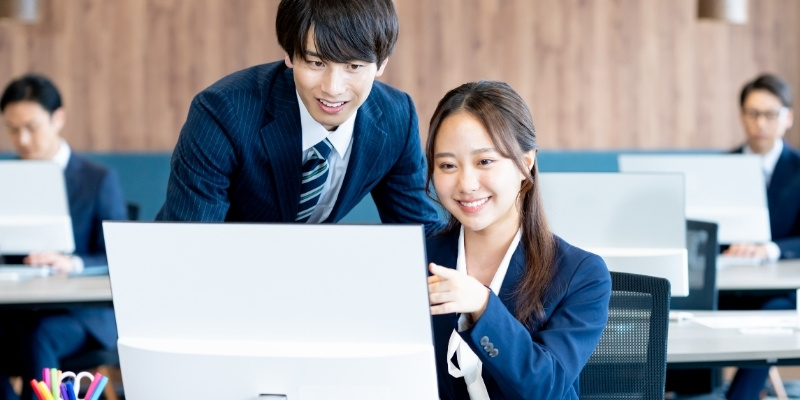 仕事中の男女がPCを見ている写真