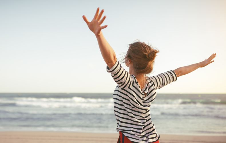 海岸で伸びをする女性