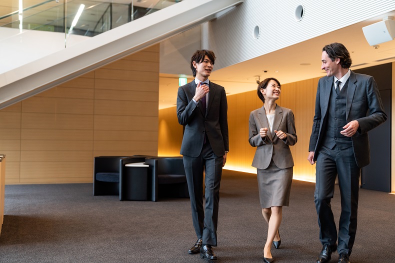 外国のビジネスマンと社内を歩く男女のビジネスパーソンの写真