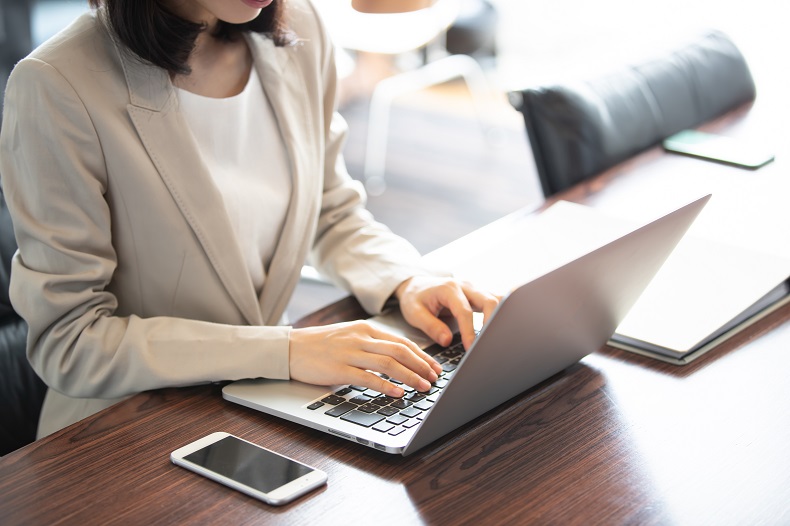 ノートPCを操作するビジネスウーマンの写真