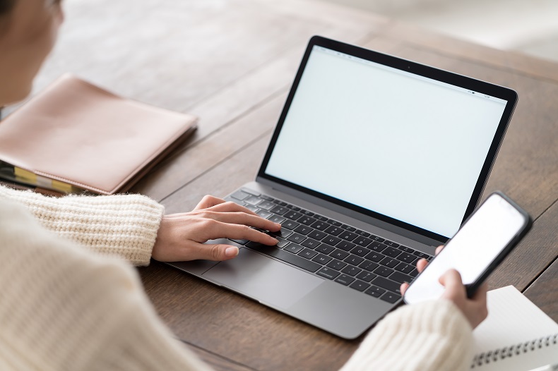 スマホとノートPCを見ている女性の写真
