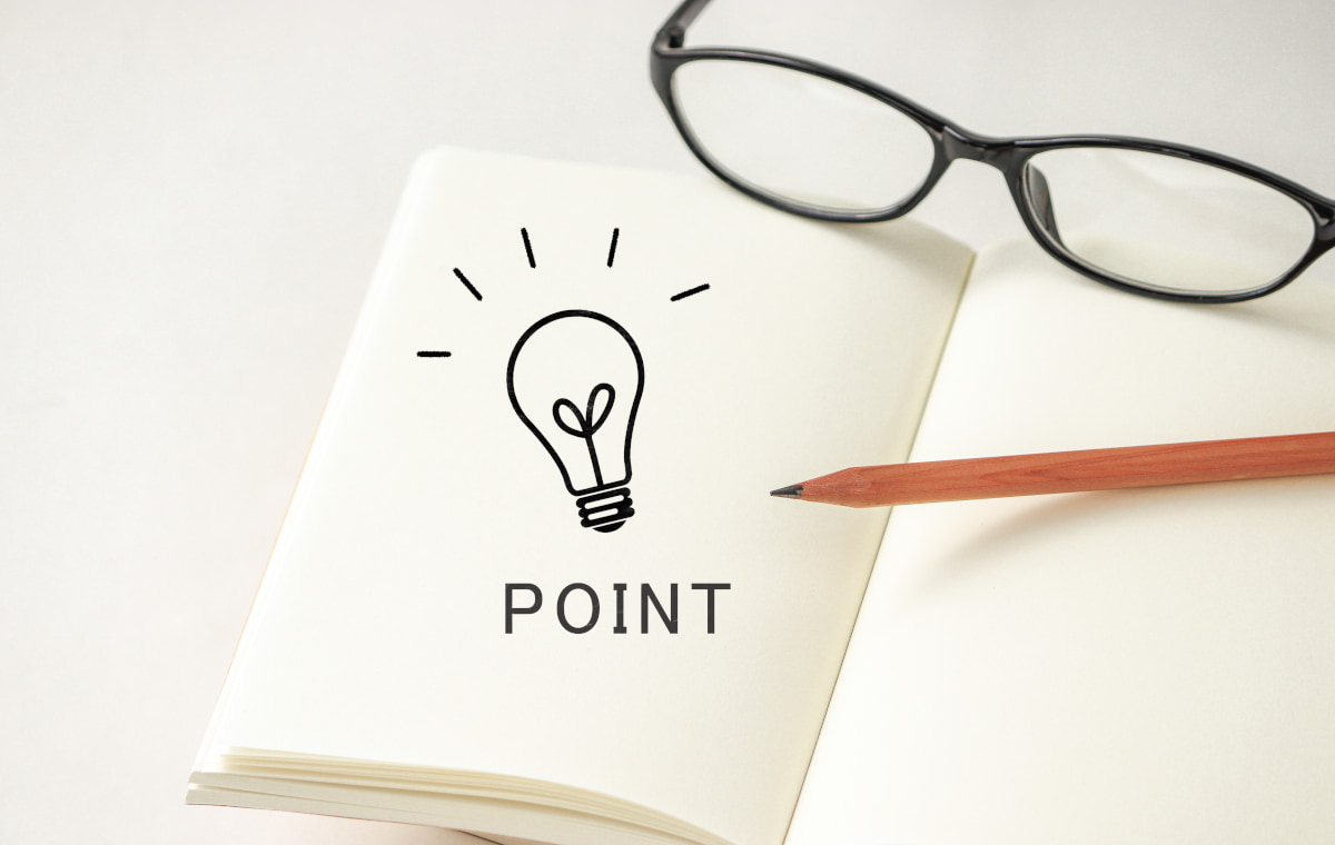 白いノートに電球とPOINTという文字が書かれている写真。脇にメガネがおかれている
