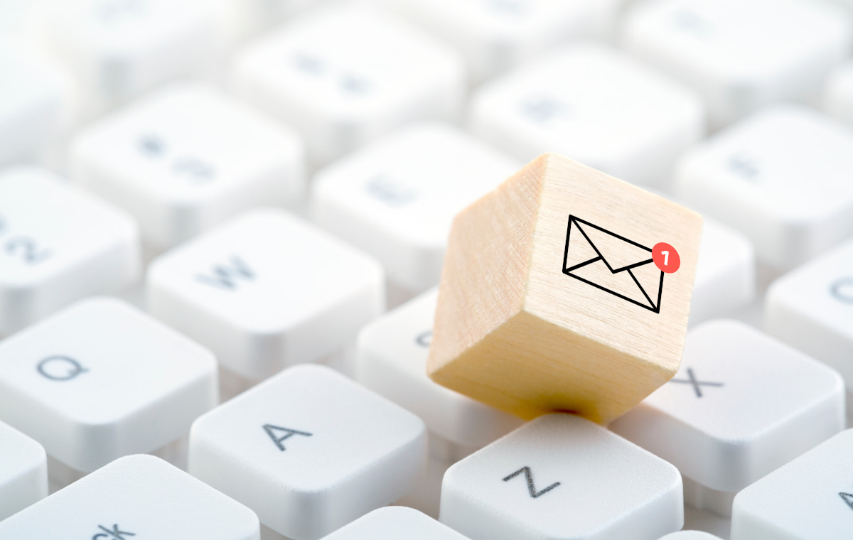 キーボードの間に封筒マークが描かれた木のオブジェが置かれている写真