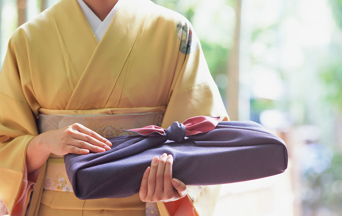 風呂敷で包んだ品物を持った着物の女性