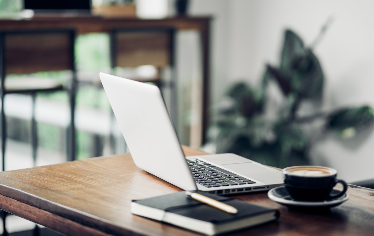 ノートパソコンとコーヒーが置かれたデスク