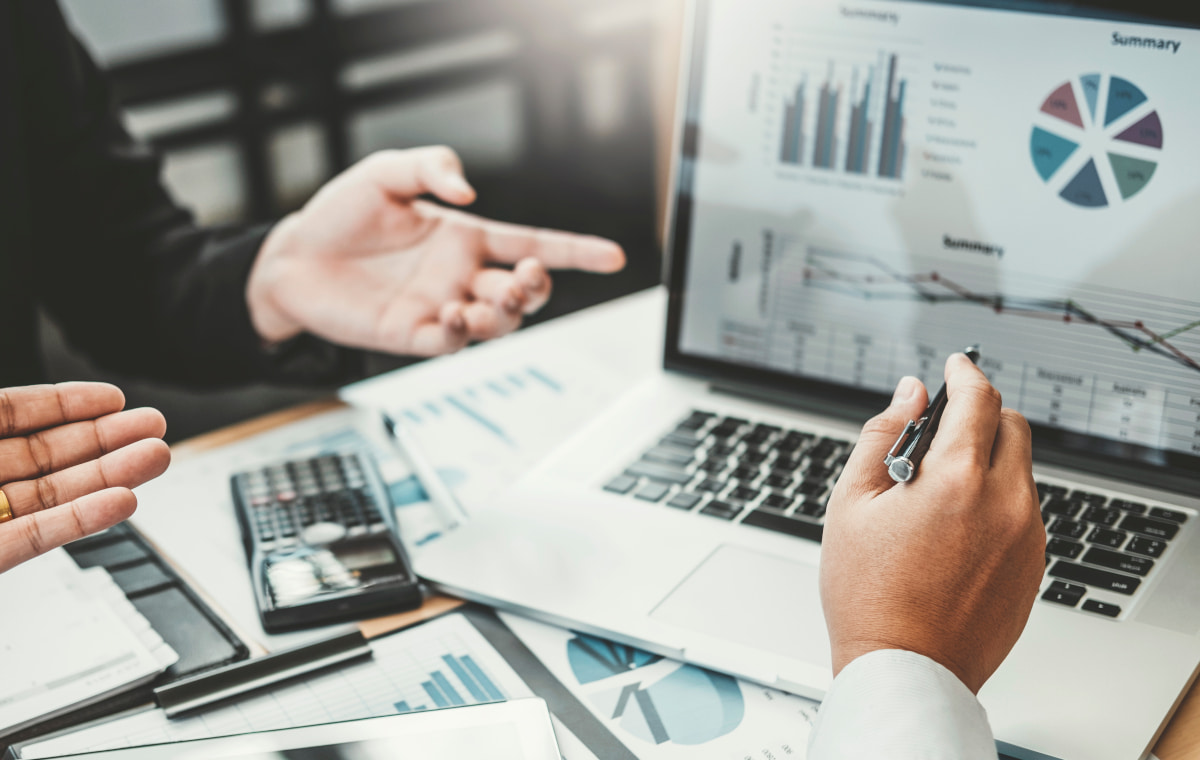 ノートパソコンと資料を見ながら会議する人々の写真