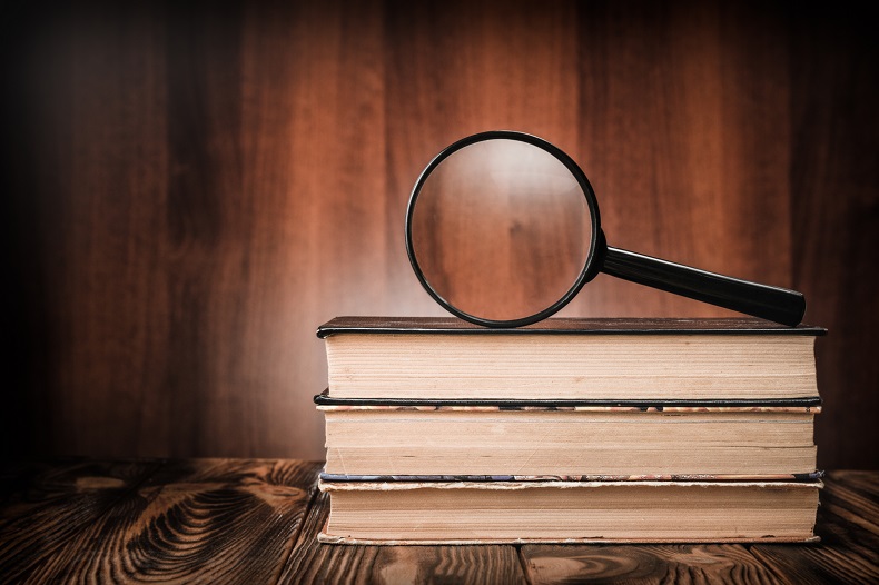 積まれた本と虫眼鏡