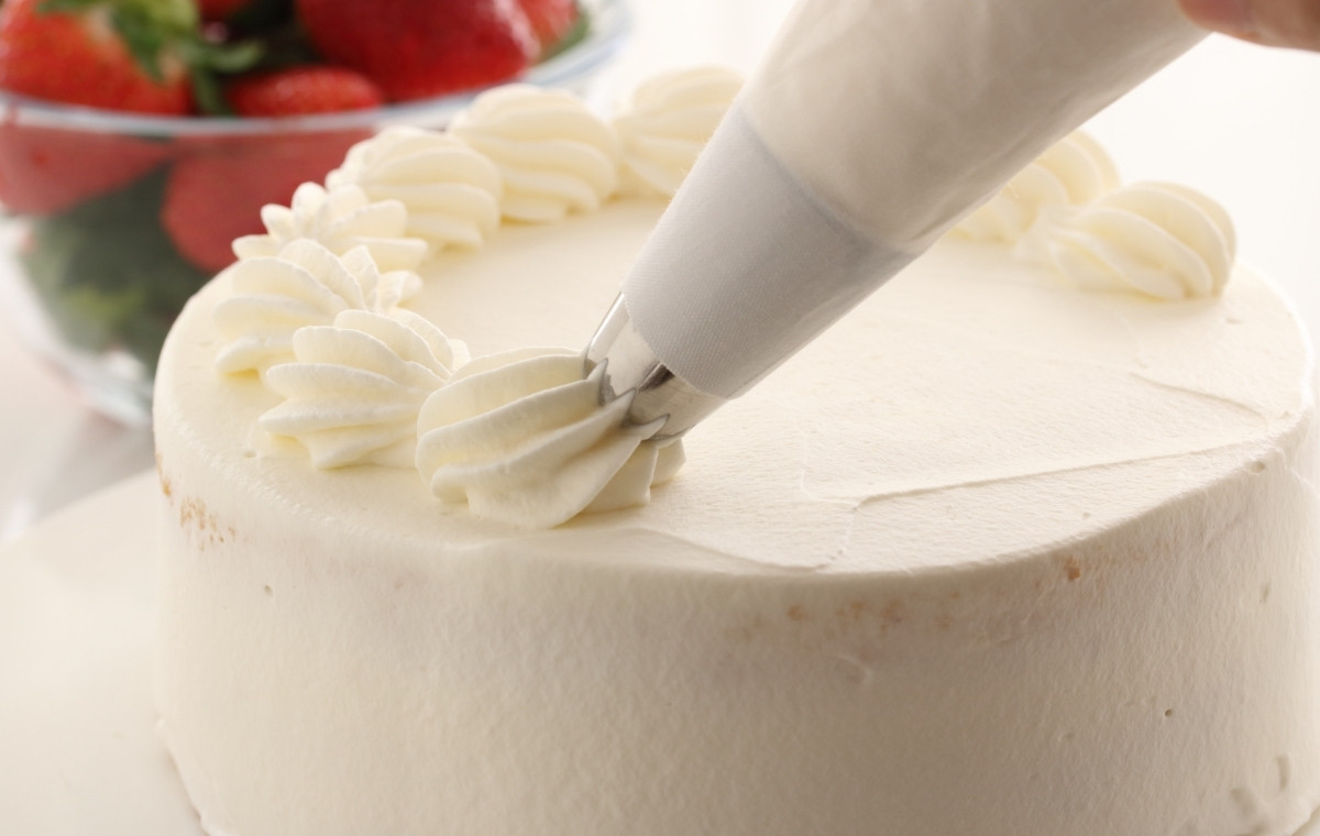 ケーキの上にクリームを絞っている写真