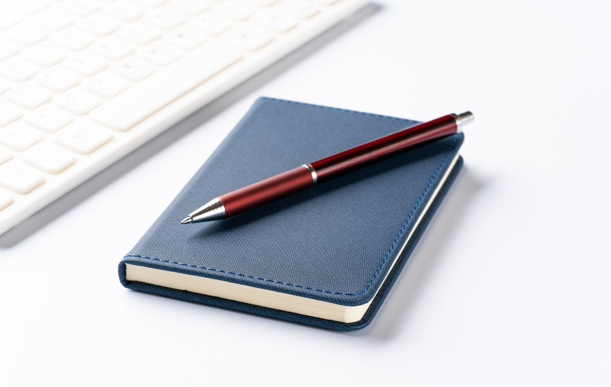 手帳とペンとPCキーボードの写真