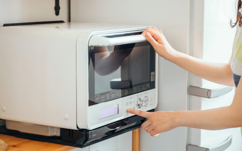 電子レンジを操作する女性の写真