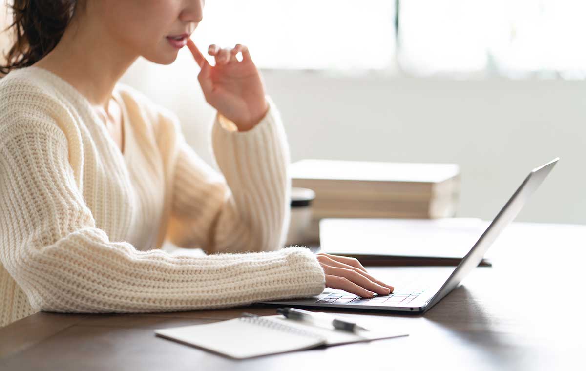 ノートを広げてノートパソコンを見ている女性の写真