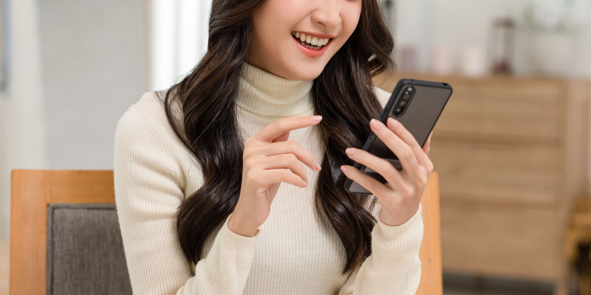 スマホを見ながら笑っている女性の写真