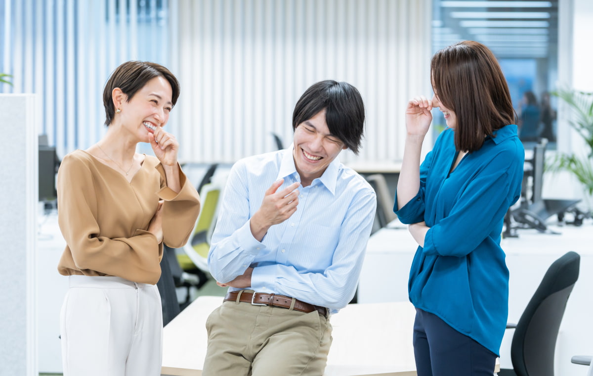 オフィスで談笑する女性二人と男性一人の写真