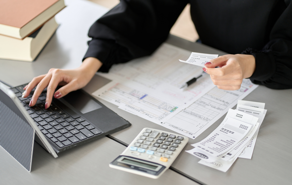 レシートや領収書をPCと電卓で整理中の女性の写真