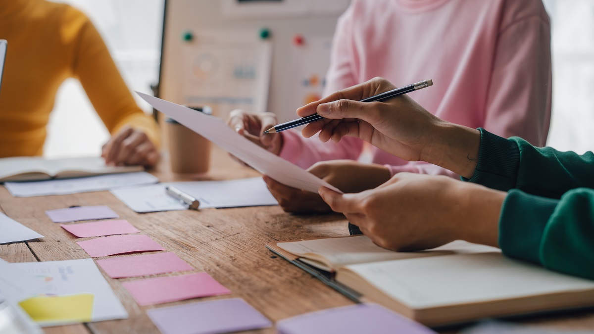 資料を広げて会議をしている人々の手元のイメージ写真