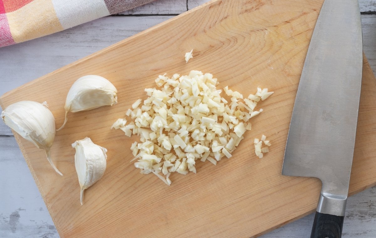 まな板の上にきざんだにんにくと包丁が置かれている写真