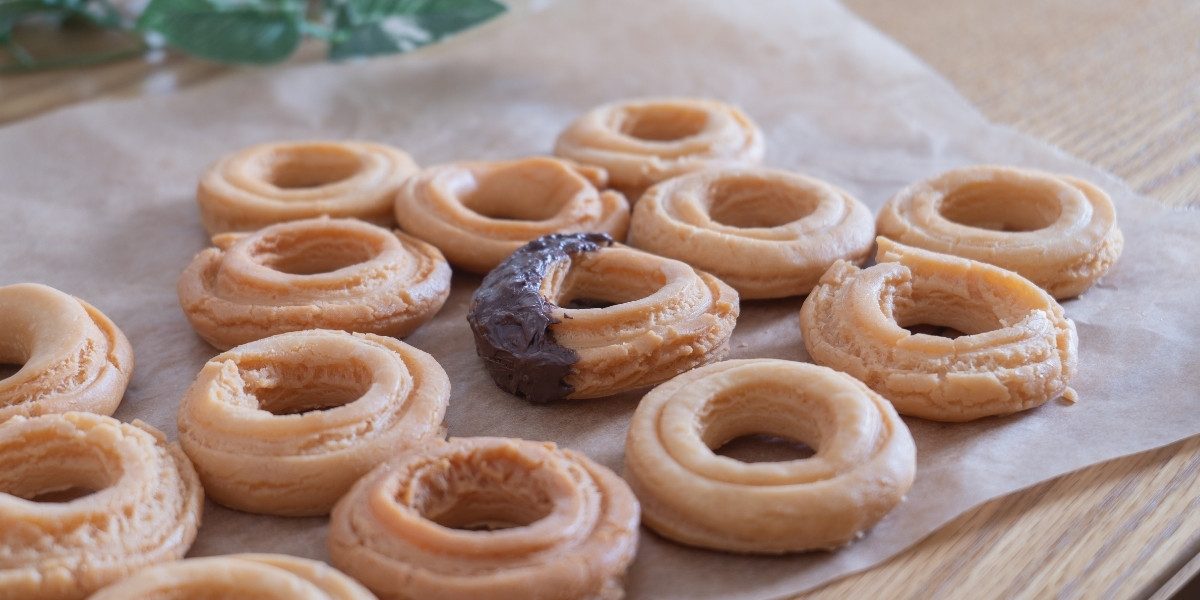 クッキングシートの上に焼けたおいしそうなドーナツが並んでいる写真