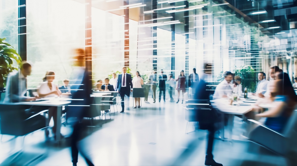 ビジネスパーソンが行き来したり、テーブルを囲んで話したりしている開放的な空間のイメージ画像