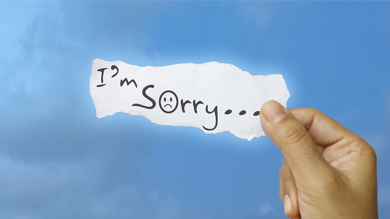 「I'm Sorry…」と書かれた紙を持った手の写真