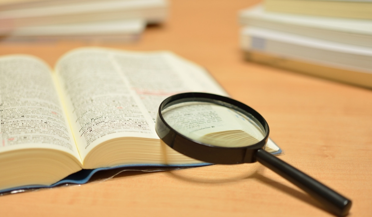 開いた辞書の上にルーペがおかれている写真