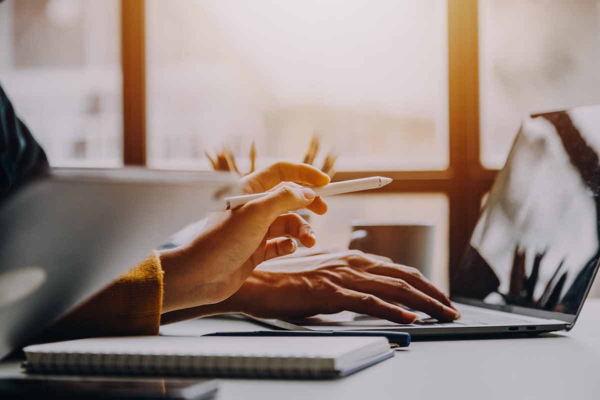 ノートパソコンを操作している人、タブレットペンでその画面を指している人の手元写真