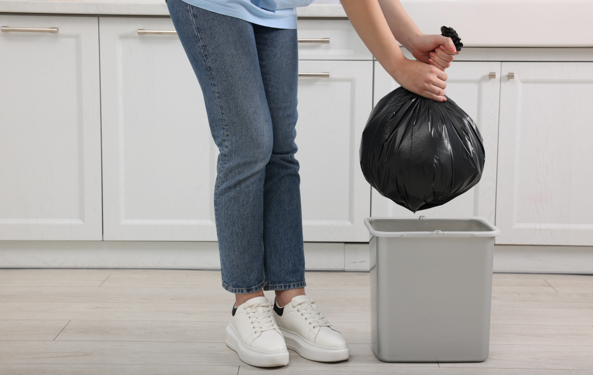 ゴミ箱からゴミ袋を取り出す女性の写真