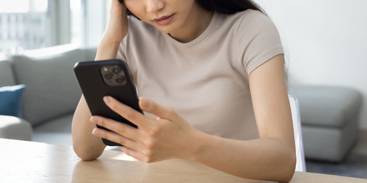 スマホを見ながら「はぁ？」というリアクションをする女性の写真